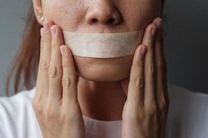 woman with mouth sealed in adhesive tape. Free of speech, freedom of press, Human rights, Protest dictatorship, democracy, liberty, equality and fraternity concepts photo