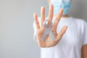 Brain Cancer Awareness month, woman hand holding grey color Ribbon for supporting people living. Healthcare and World cancer day concept photo