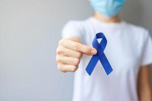 marzo mes de concientización sobre el cáncer colorrectal, mujer sosteniendo una cinta azul oscuro para apoyar a las personas que viven y están enfermas. concepto de salud, esperanza y día mundial contra el cáncer foto