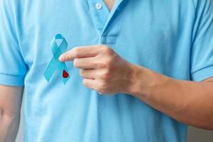 noviembre, mes de concientización sobre el día mundial de la diabetes, hombre que sostiene una cinta azul claro con forma de gota de sangre para apoyar a las personas que viven, previenen y enferman. cuidado de la salud, concepto del día del cáncer de próstata foto