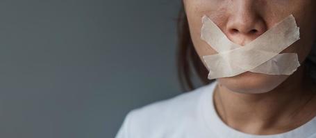 woman with mouth sealed in adhesive tape. Free of speech, freedom of press, Human rights, Protest dictatorship, democracy, liberty, equality and fraternity concepts photo