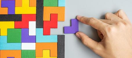 hand connecting geometric shape block with colorful wood puzzle pieces. logical thinking, business logic, Conundrum, decision, solutions, rational, mission, success, goals and strategy concepts photo