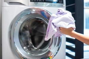Housewife Woman hand holding clothes inside Washing Machine in laundry room photo