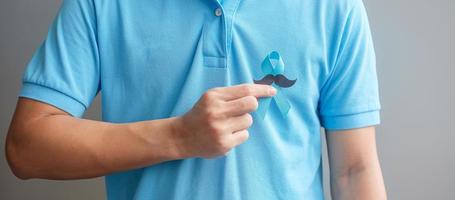 November Prostate Cancer Awareness month, Man holding Blue Ribbon with mustache for supporting people living and illness. Healthcare, International men, Father and World cancer day concept photo