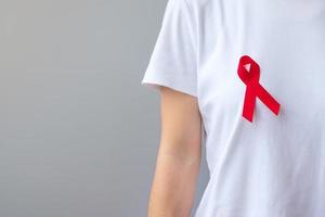 mano sosteniendo la cinta roja para el día mundial del sida de diciembre, el mes de concientización sobre el cáncer de mieloma múltiple y la semana nacional de la cinta roja. concepto de salud y día mundial del cáncer foto