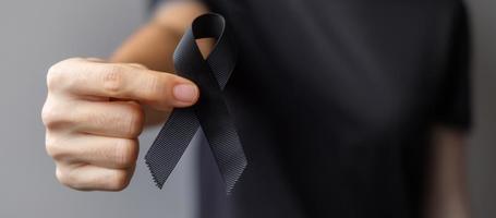 Woman holding black Ribbon for Melanoma and skin cancer, Vaccine injury awareness month, grief and rest in peace. Healthcare and Racist concept photo