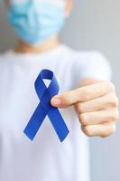 March Colorectal Cancer Awareness month, Woman holding dark Blue Ribbon for supporting people living and illness. Healthcare, hope and World cancer day concept photo