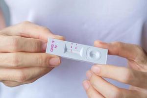 hombre que sostiene un kit de prueba rápida de antígeno con resultado negativo durante la prueba de hisopo covid-19. coronavirus auto nasal o prueba casera, concepto de bloqueo y aislamiento del hogar foto