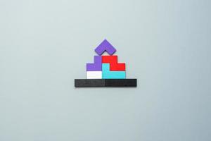 Home shape block with colorful wood puzzle pieces on gray background. logical thinking, business logic, solutions, rational, house, real estate and strategy concepts photo