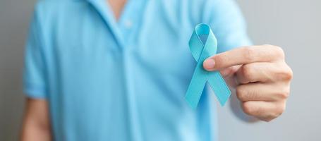 noviembre mes de concientización sobre el cáncer de próstata, hombre con camisa azul con la mano sosteniendo una cinta azul para apoyar a las personas que viven y están enfermas. cuidado de la salud, hombres internacionales, padre y concepto del día mundial del cáncer foto