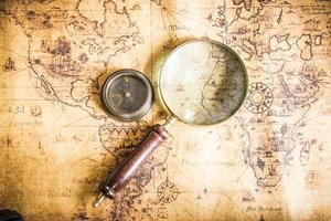 Old vintage retro compass and magnifying glass on ancient map.The map used for background is in Public domain. photo