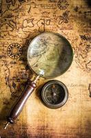 Old vintage retro compass and magnifying glass on ancient map.The map used for background is in Public domain. photo