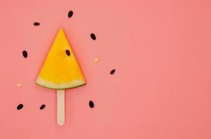 Slice of yellow watermelon on ice cream wooden stick with seeds for summer time. photo