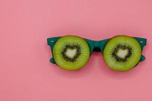 Two slice green kiwi fruits put on green sunglasses set as face with eyes. photo