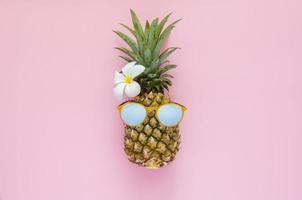 Pineapple wearing sunglasses with white frangipani flower photo