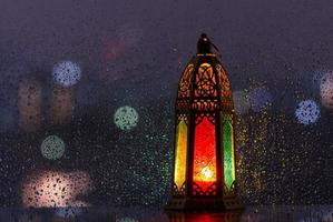 Lantern put at window with rain drop at night photo