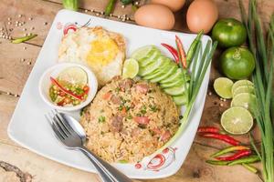 fried rice with vegetables, meat and fried eggs served on a plate with chopsticks photo