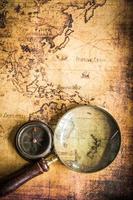 Old vintage retro compass and magnifying glass on ancient map.The map used for background is in Public domain. photo