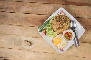 fried rice with vegetables, meat and fried eggs served on a plate with chopsticks photo