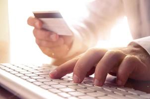 Closeup of mans hands holding credit card and using computer keyboard. Concept for e-commerce, online shopping, e-banking, internet security. photo