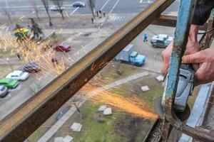 un trabajador corta metal con un molinillo. foto