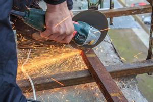 un trabajador corta metal con un molinillo. foto