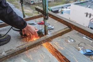 un trabajador corta metal con un molinillo. foto