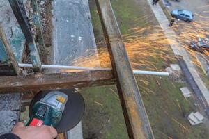 un trabajador corta metal con un molinillo. foto