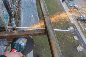 un trabajador corta metal con un molinillo. foto