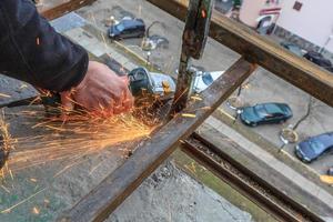 un trabajador corta metal con un molinillo. foto