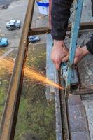 un trabajador corta metal con un molinillo. foto