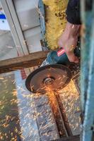 A worker cuts metal with a grinder. photo