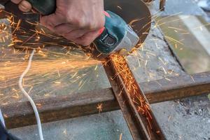 un trabajador corta metal con un molinillo. foto