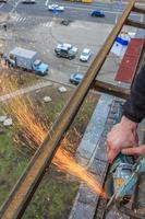 un trabajador corta metal con un molinillo. foto