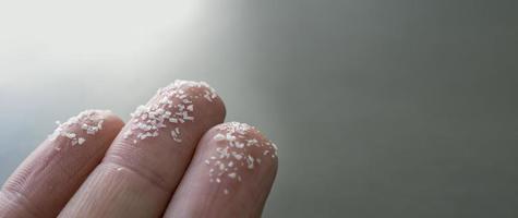 Close-up side shot of microplastics on human fingers. Concept for water pollution and global warming. Climate change idea. Soft focus on a bunch of micro plastic that cannot be recycled. photo