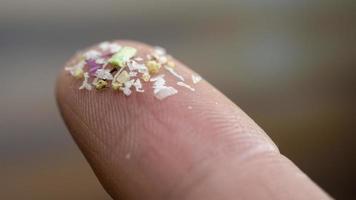 Close-up side shot of microplastics on human fingers. Concept for water pollution and global warming. Climate change idea. Soft focus on a bunch of micro plastic that cannot be recycled. photo