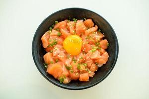 salmón con arroz de huevo en un bol negro sobre un fondo blanco foto