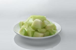 Small pieces of melon in a white plate on white background. photo