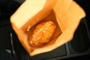 Croissant in a paper bag placed Vehicle Interio car. photo