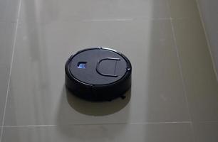 Black robot vacuum cleaner on tiled floor photo