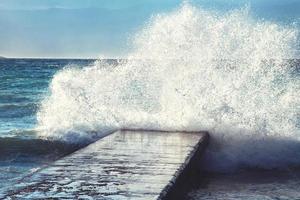 grandes olas rompiendo en el muelle de piedra, en clima tormentoso. foto