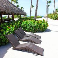 Relax on tropical beach in the sun on deck chairs under umbrella. photo