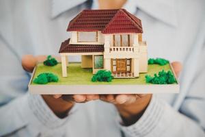 A real estate agent with House model photo