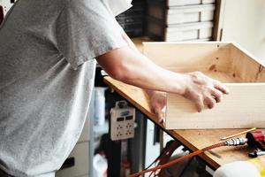 A carpenter measures the planks to assemble the parts, and build a wooden table for the customer. photo