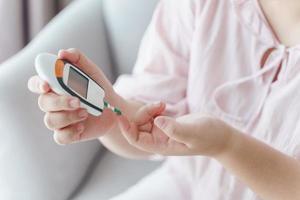 Asian woman checking blood sugar level by Digital Glucose meter, Healthcare and Medical, diabetes, glycemia concept photo