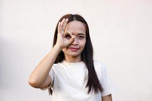 mujer asiática sonriendo alegremente levante la mano como señal de estar bien. foto