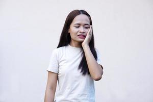 Asian woman with toothache touches cheek with her hand photo