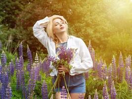 Woman walks in the garden full of lupines photo