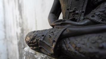 A slow moving shot of a buddha statue sitting in a lotus pose.
