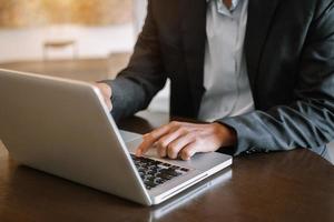 las manos del hombre están escribiendo en una computadora portátil y sosteniendo una tableta foto